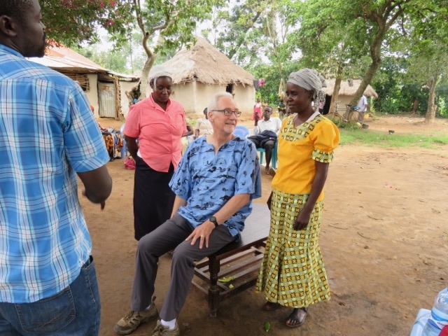 Roger sitting between two standing women