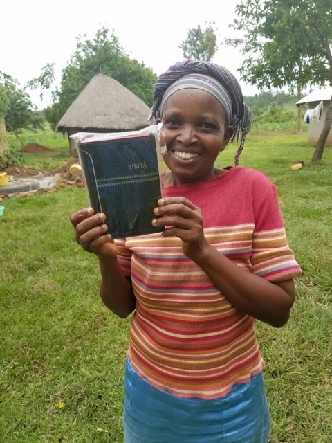a smiling woman holding a new Bible